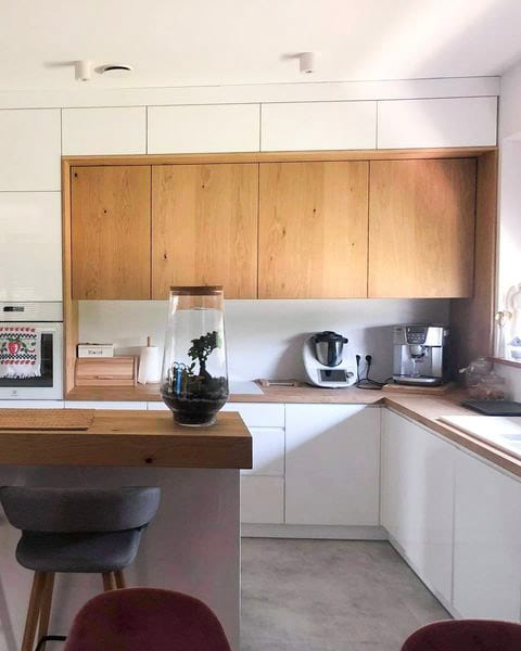 Biała kuchnia z drewnianymi szafkami i wyspą